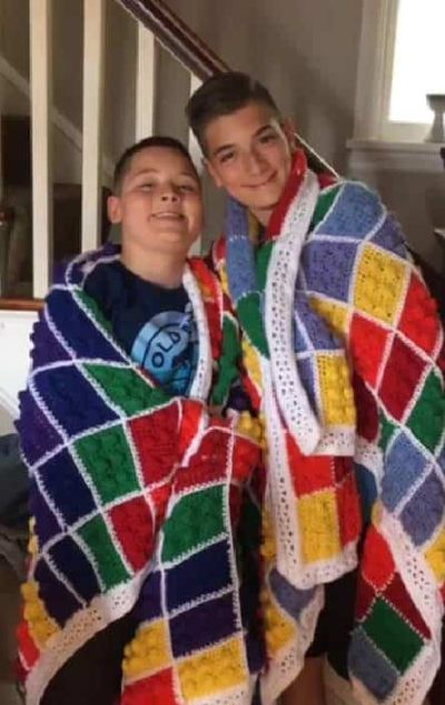 19989692_448817182171844_4165668017430288072_n Two people holding a finished LEGO-inspired crochet blanket