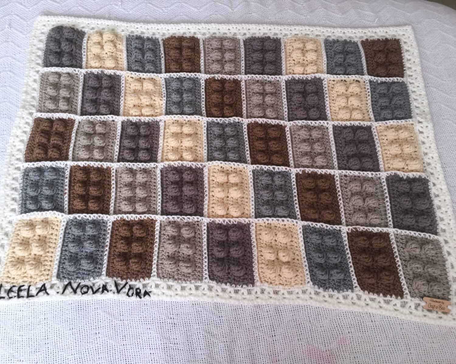 Gray and white LEGO-inspired crochet block blanket with textured brick squares